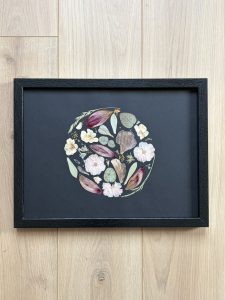 Une composition florale circulaire réalisée à la main à partir de fleurs et feuillages délicatement pressés. Les nuances douces de rose poudré, de bordeaux et de vert eucalyptus se déploient harmonieusement sur un fond noir profond, créant un contraste élégant et contemporain. Chaque élément est minutieusement disposé pour former un équilibre naturel et raffiné. Encadrée dans un cadre noir intemporel, cette création devient une pièce décorative unique, à la fois artistique et poétique, qui sublime la beauté fragile des fleurs préservées.