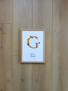 n monogramme floral réalisé à la main à partir de véritables fleurs pressées. La lettre G, délicatement composée de pétales roses et jaunes, est encadrée de bois naturel pour une finition douce et épurée. Personnalisé avec le prénom Giulianna et sa date de naissance, ce cadre devient un souvenir unique et intemporel, parfait pour célébrer une naissance avec poésie.