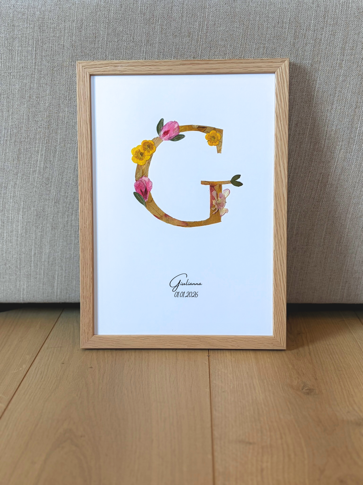 n monogramme floral réalisé à la main à partir de véritables fleurs pressées. La lettre G, délicatement composée de pétales roses et jaunes, est encadrée de bois naturel pour une finition douce et épurée. Personnalisé avec le prénom Giulianna et sa date de naissance, ce cadre devient un souvenir unique et intemporel, parfait pour célébrer une naissance avec poésie.