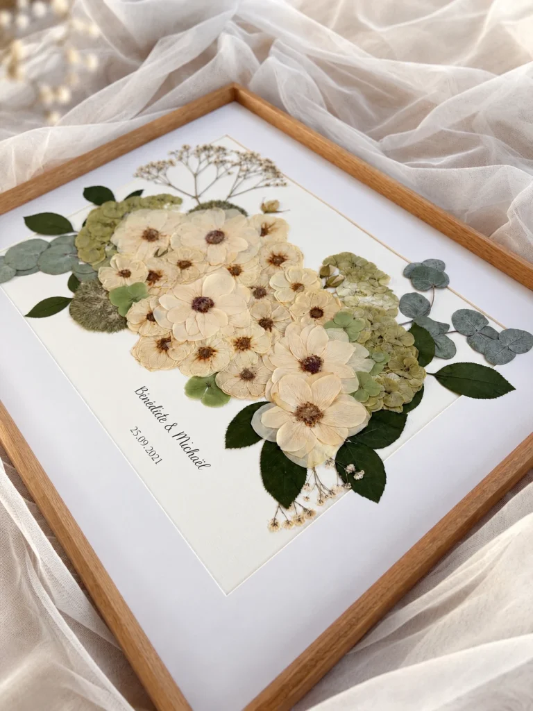 Détail d'un herbier de mariage : fleurs blanches, hortensias verts et eucalyptus pressés sous cadre
